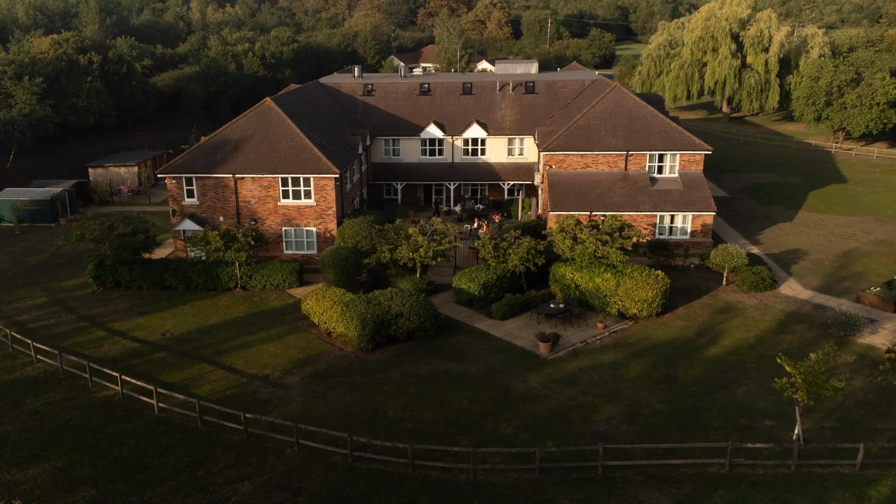 Meadowbanks Care Home and its gardens from above at golden hour, surrounded by Essex countryside